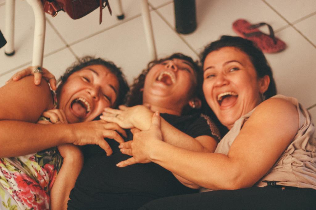 Image of three Hispanic women laughing together and embracing.
