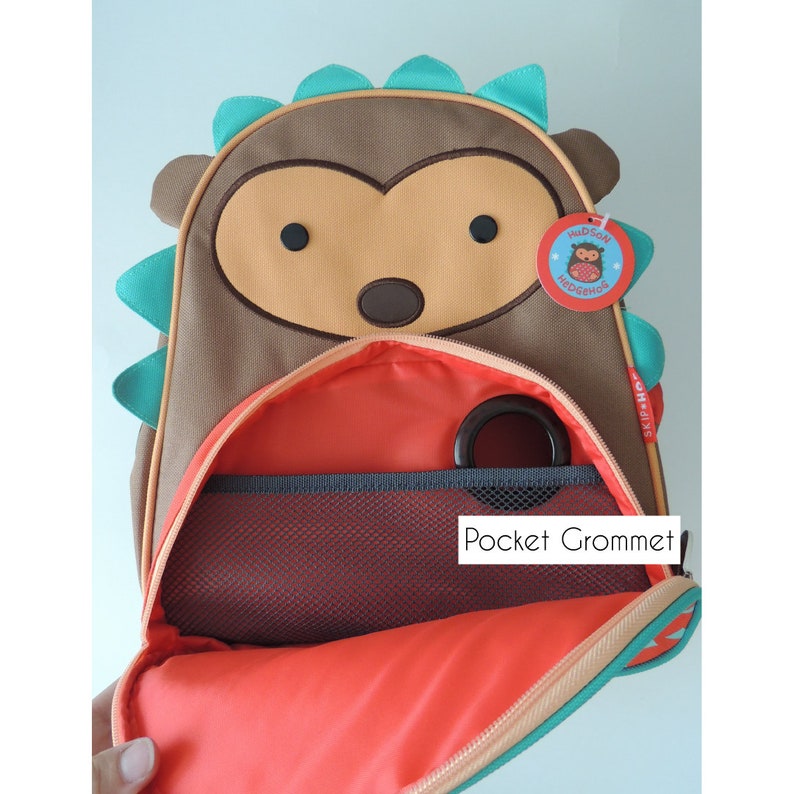 Image of small hedgehog children's backpack demonstrating a grommet opening for feeding tube, with link to Etsy seller's site. 