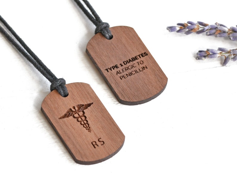 Image shows two wooden dog tag medical alert necklaces with stamped diagnoses and logo, and link to Etsy seller.