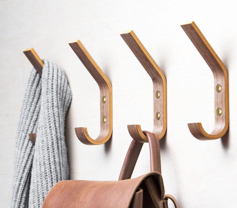 Image shows four wooden coat hooks hung on a wall.