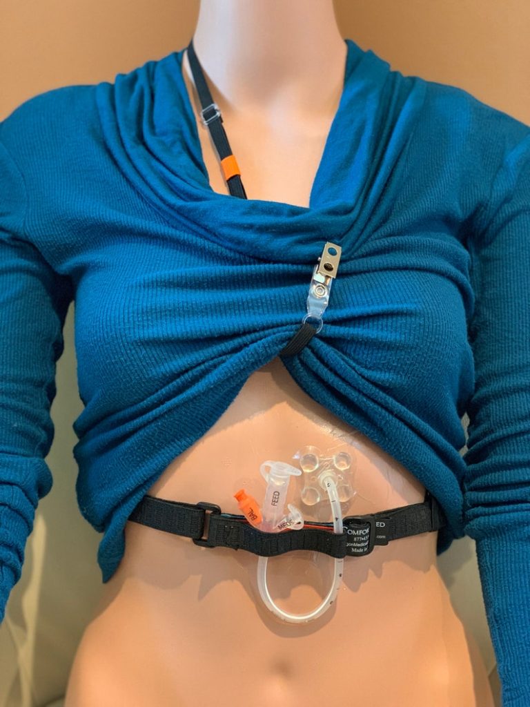 Image of black strap harness for holding adult g-button feeding tube, with link to Etsy seller.
