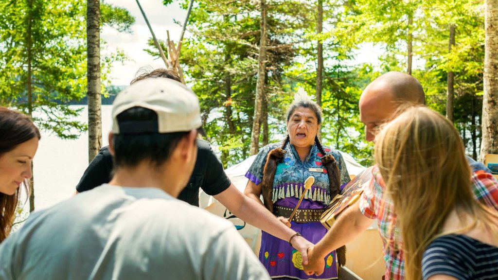 Image of indigenous woman chanting for dancing tourists. 
