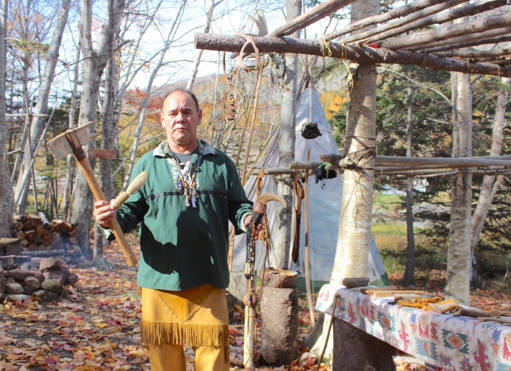 Image of indigenous man holding handcrafted traditional items. 