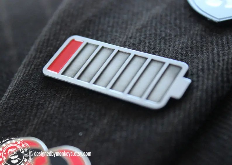 Image of battery charging enamel pin, with link to Etsy seller.
