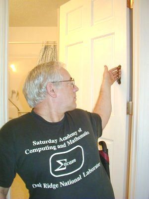 Image of man in a wheelchair pulling handle on doorway to close after entering. 